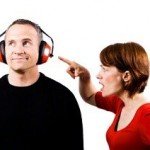 Woman points at man's face as man listens to headphones