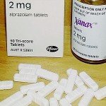 Bottle of Xanax on wooden table surrounded by white pills