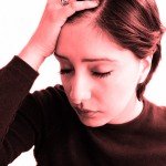 Closeup of woman with eyes closed holding hand to head