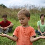 Young boy stands in front of parents as parents sit behind him