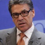Rick Perry wearing glasses and orange tie during interview
