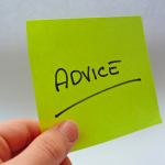 A hand holds green post it note with the word Advice underlined