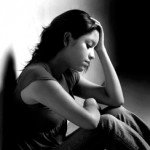 Black and white image of teen girl holding head