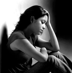 Black and white image of teen girl holding head