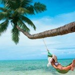 Woman relaxes in hammock from a palm tree