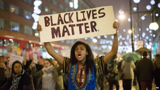 Woman holds sign in street reading Black Lives Matter