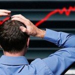 Man stands holding head in frustration at stock market decrease
