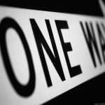 Closeup of a One Way arrow sign focused on the word One