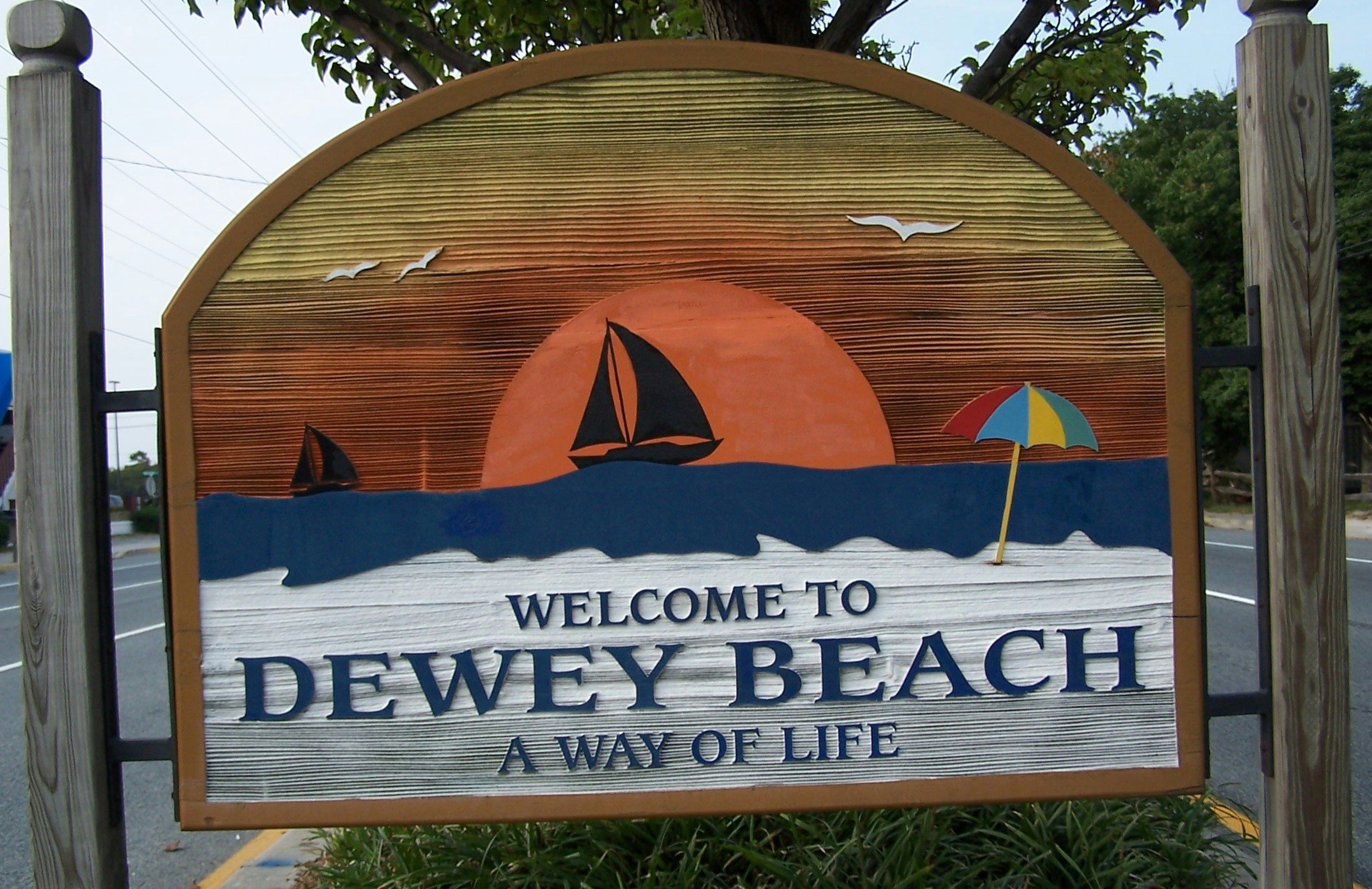Welcome to Dewey Beach sign with sailboats and an umbrella