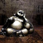 A laughing Buddha statue sitting on wooden table