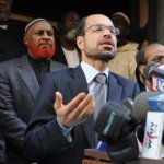 Man gives speech with support standing behind him