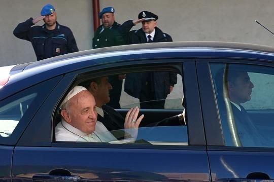 Pope Francis riding in backseat of car as bystanders salute