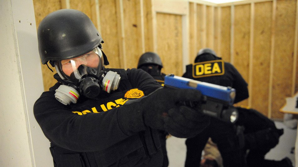 Police wearing gas mask aiming gun at unknown target