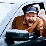 Man clenches fist with angry look while in car