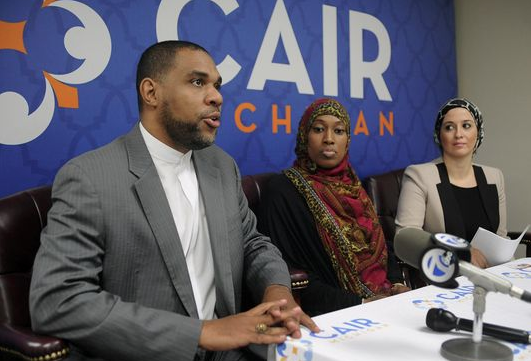 Three people sit at table during speaking event