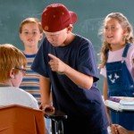 Young boy bullies classmate while others watch