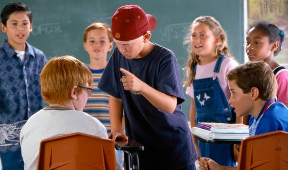 Young boy bullies classmate while others watch