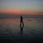 Person walking on the beach during a sunset