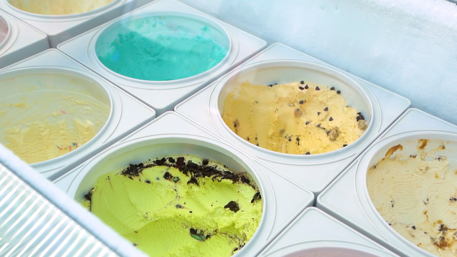 Tubs of ice cream on display in a ice cream cooler.