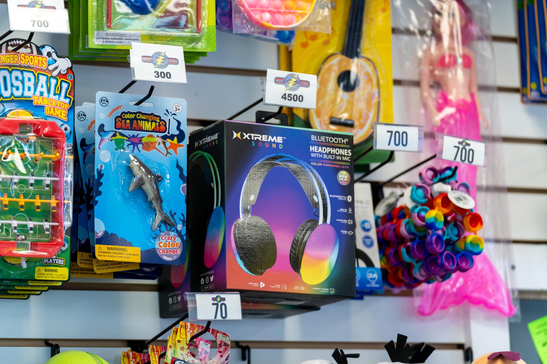 Arcade prizes on a shelf, including headphones and toys.