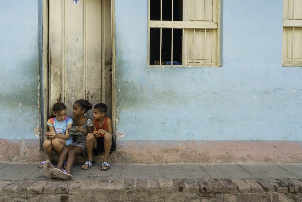three children sitting on the side of a building