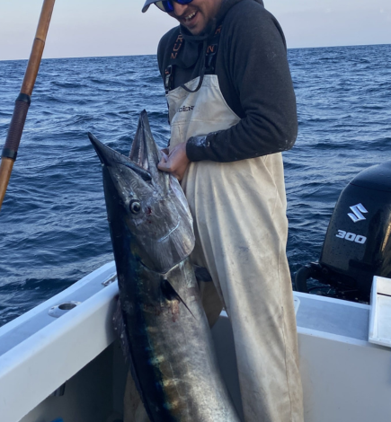 Young man holding a large fish on a charter fishing boat