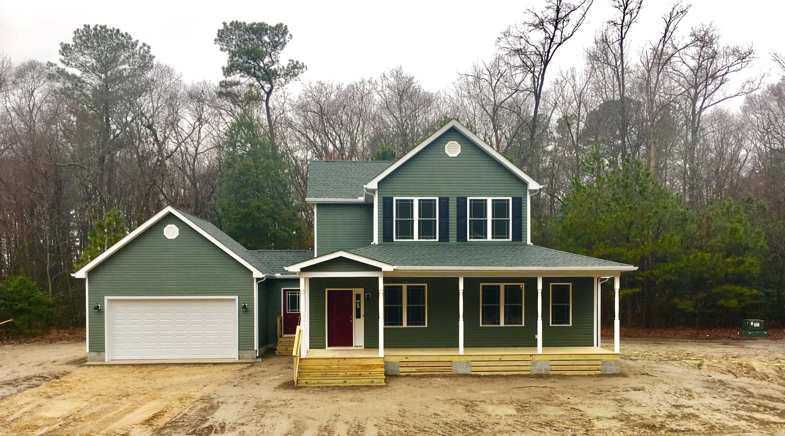 a large green house with two garages in front of it