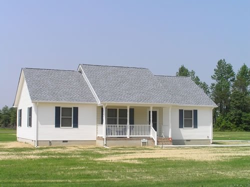 a small white house sitting on top of a lush green field