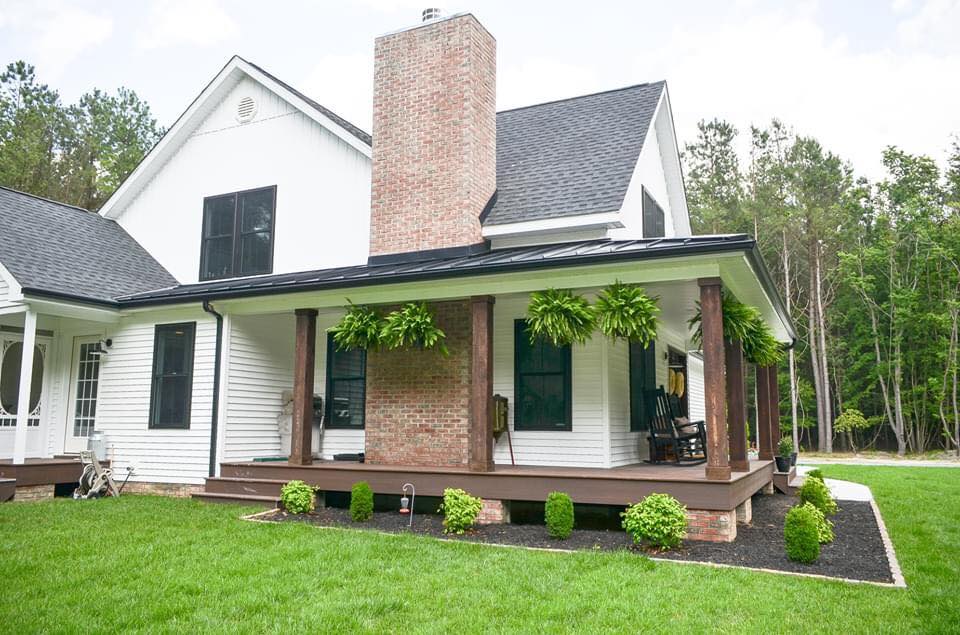 a white house with green shutters and black roof