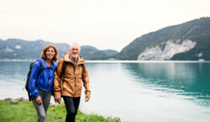 Retired couple holding hands beside a lake in the mountains