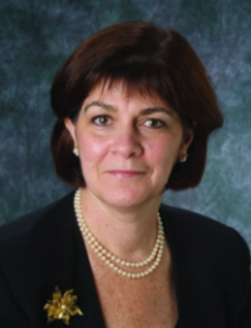 a woman in a black jacket and pearl necklace