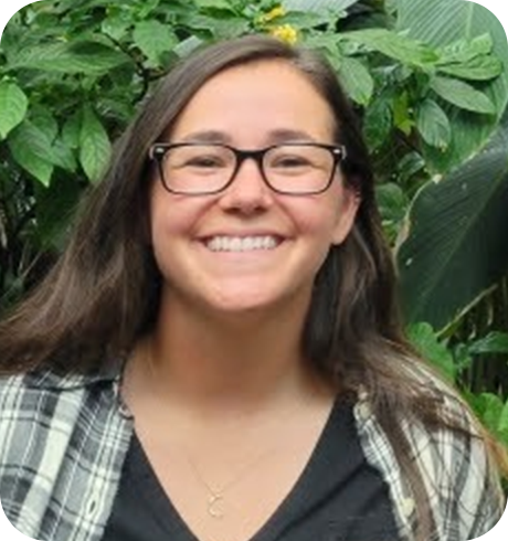 a woman wearing glasses standing in front of green plants