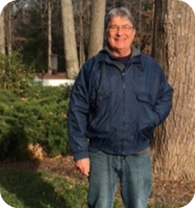 an older man standing in front of a tree