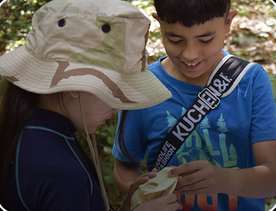 a boy and girl sharing a sandwich in the woods