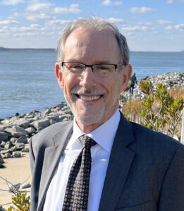 a man in a suit and tie standing by the water