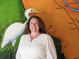 a woman standing in front of a painting of a bird
