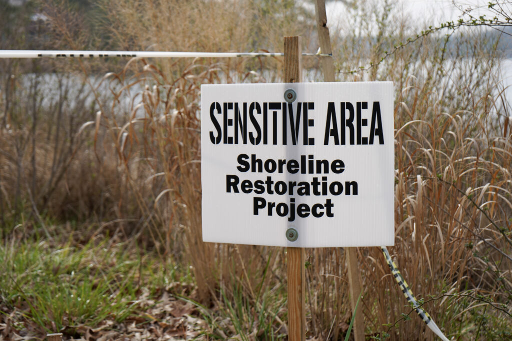 a sign that is in the grass by some water