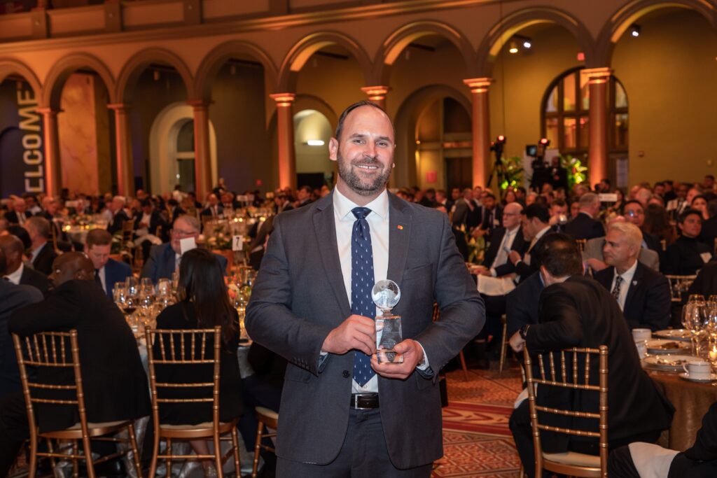 a man standing in front of a crowd holding an award
