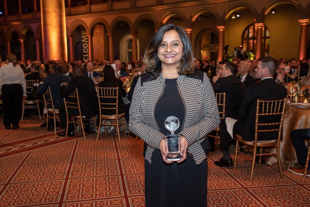 a woman holding an award in front of a room full of people