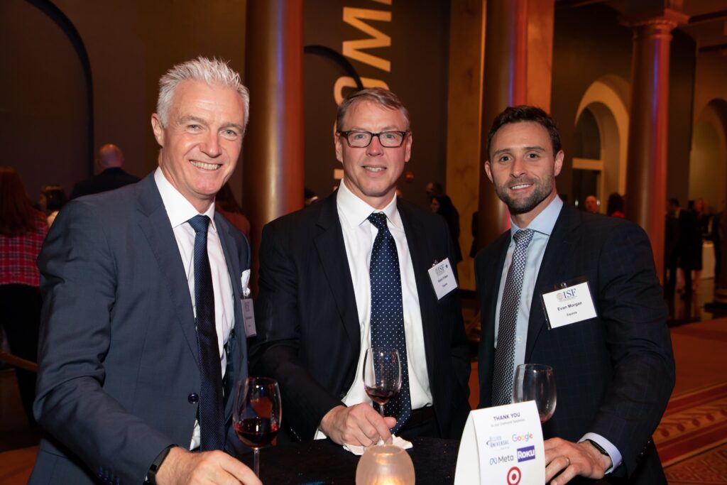three men standing next to each other holding wine glasses