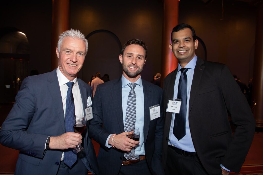 three men standing next to each other holding wine glasses