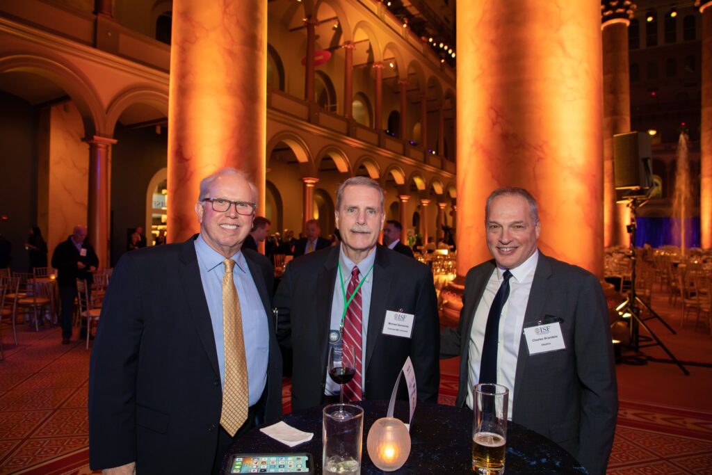 three men standing next to each other at a table