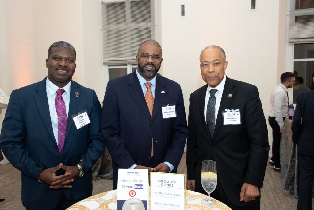 three men standing next to each other at a table