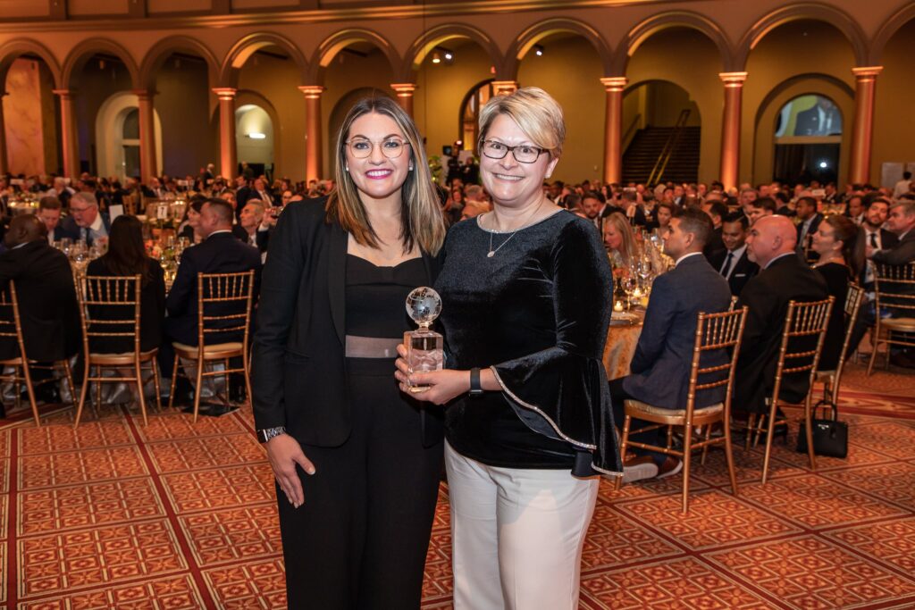 two women standing next to each other at a banquet