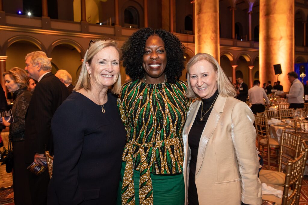 three women standing next to each other in a room