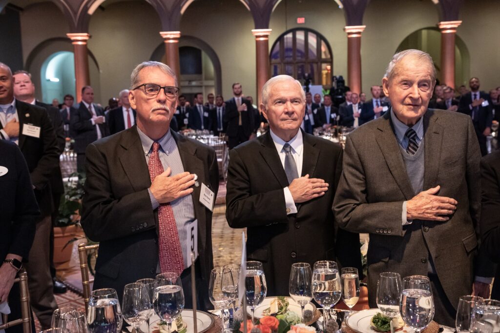three men standing next to each other at a table
