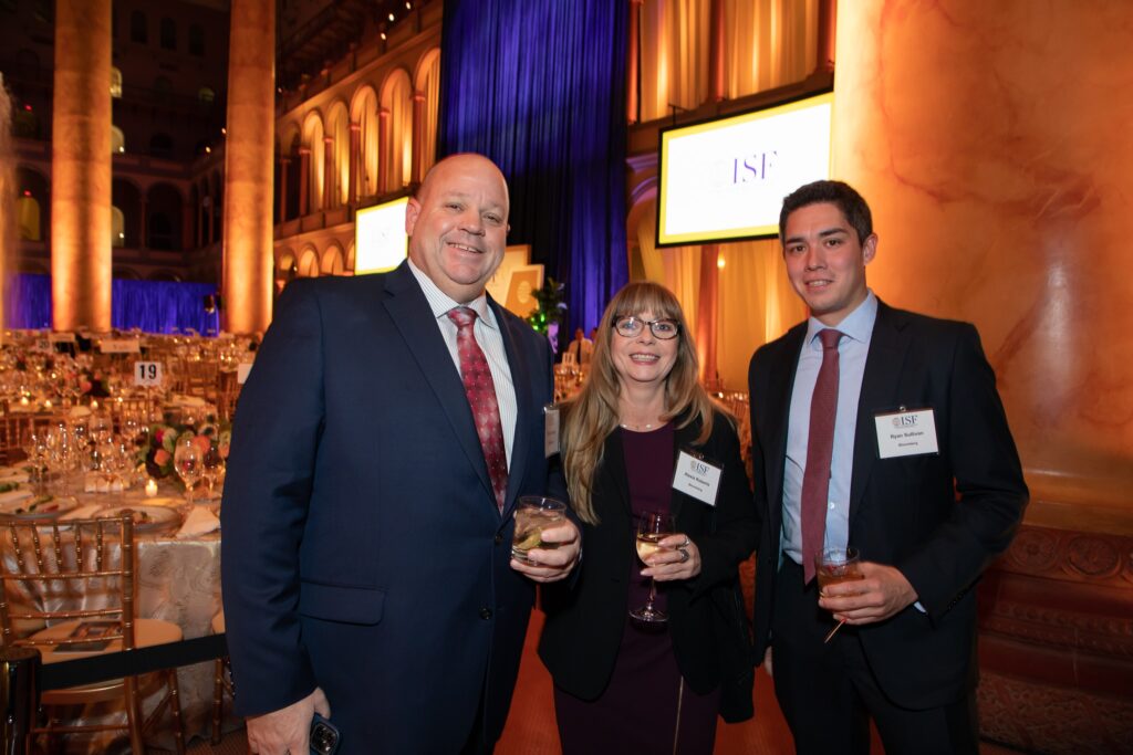 three people standing next to each other holding wine glasses