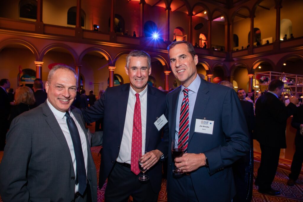 three men standing next to each other in a room
