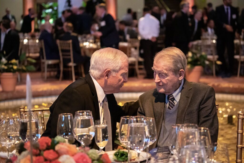 two men sitting at a table with wine glasses