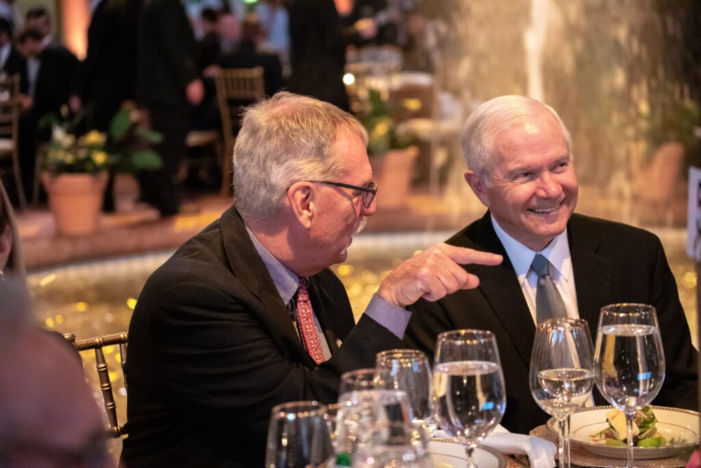 two men sitting at a table with wine glasses